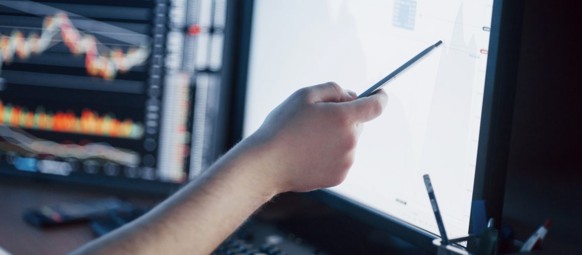 Analyzing data. Close-up of young businessman pointing on the data presented in the chart with pen while working in creative office.